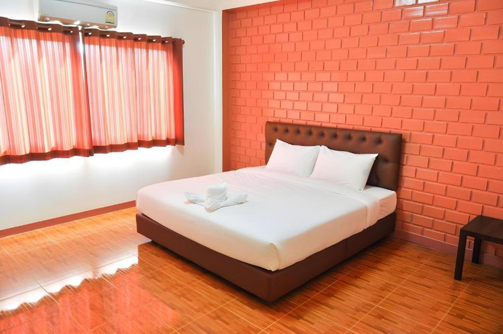 a bedroom with a bed with a brick wall at Bussarakam Place Hotel in Ban Chamun (2)