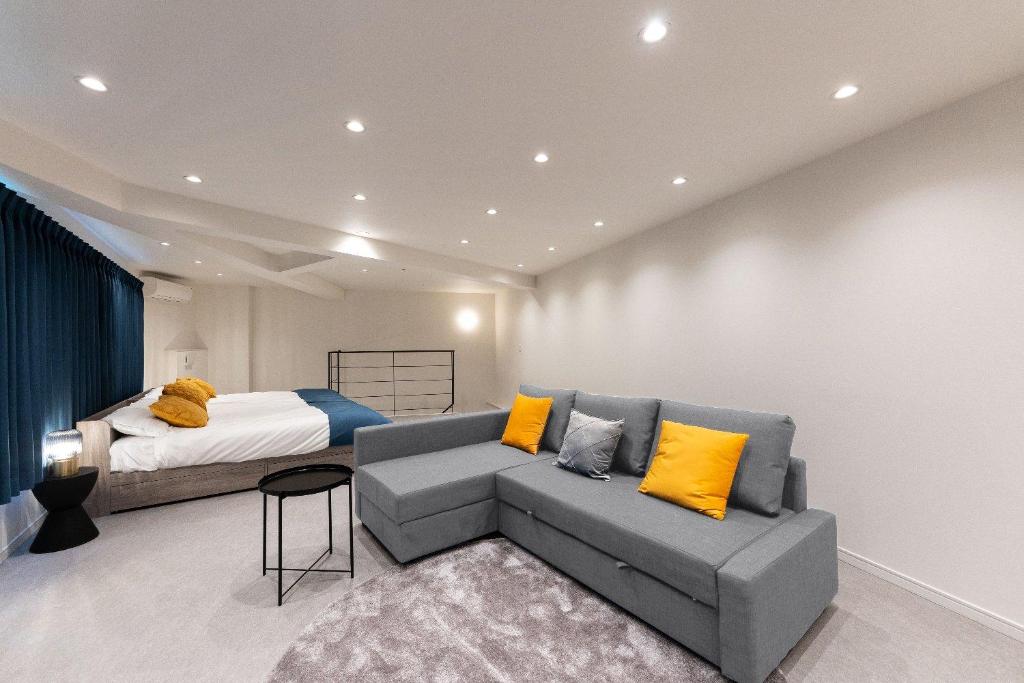a bedroom with a bed and a couch with yellow pillows at Bonheur Akasaka in Tokyo