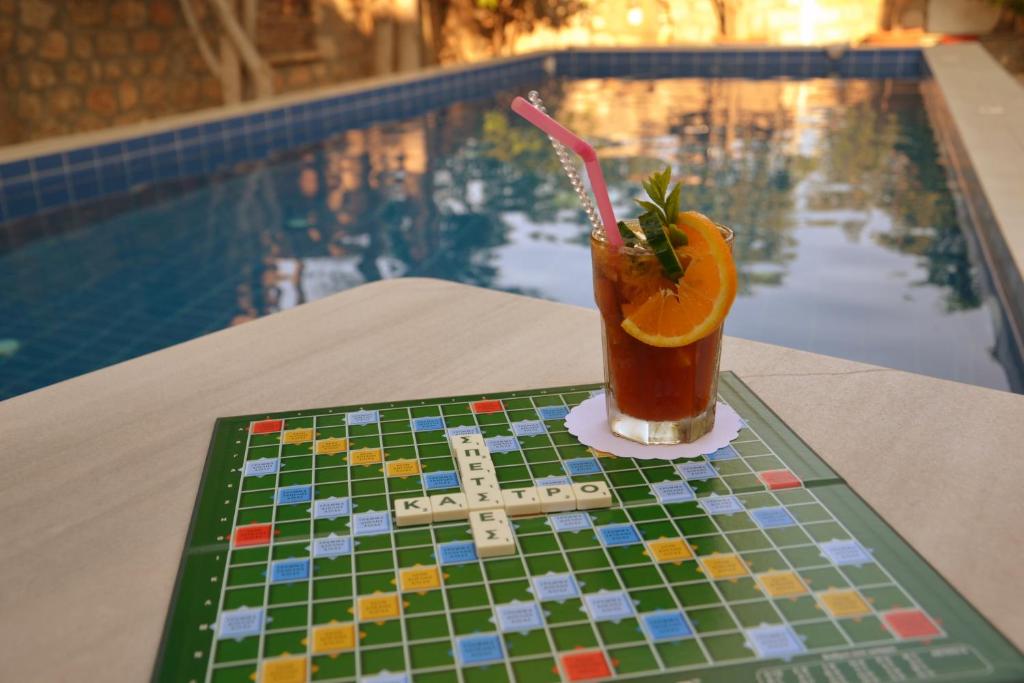 a drink on a table next to a swimming pool at Kastro Hotel in Spetses