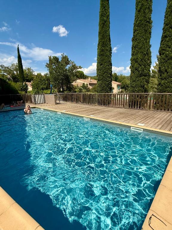 une personne se baignant dans une piscine bordée d'arbres dans l'établissement Appartement 1 chambre avec piscine, à Gréoux-les-Bains