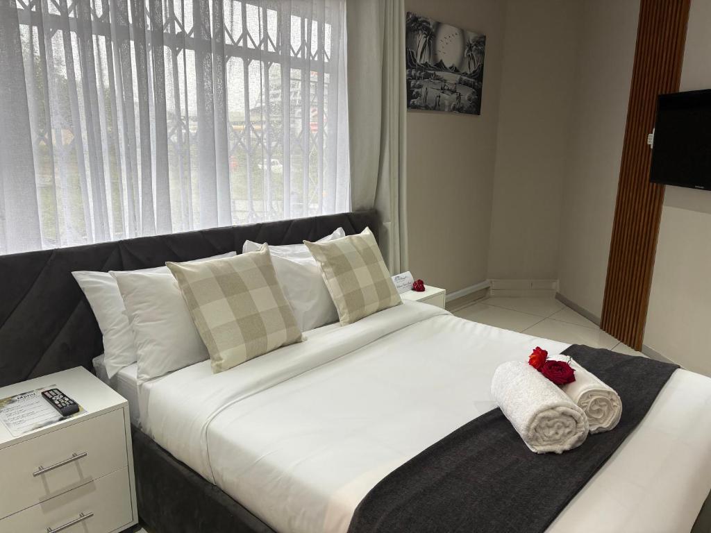 a bedroom with a large white bed with towels on it at Kilimanjaro Lodge Bed & Breakfast in Johannesburg