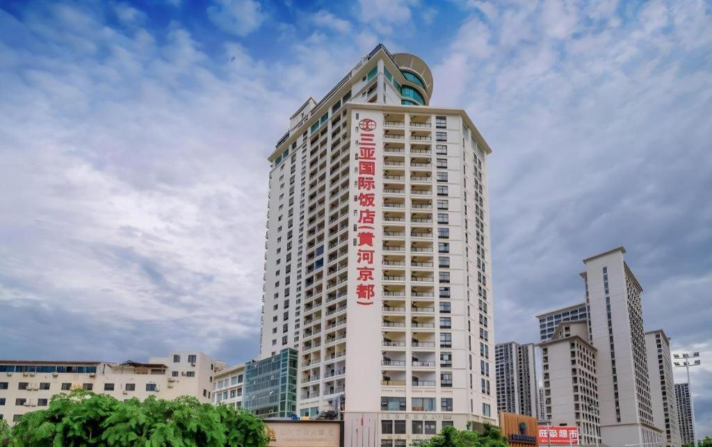 un grand bâtiment blanc avec une enseigne dessus dans l'établissement Sanya Yellow River Kyoto Hotel, à Sanya