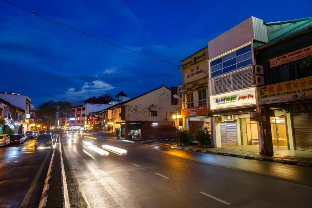 uma rua da cidade à noite com carros a conduzir pela rua em RAINFOREST Budget Stay em Kuching