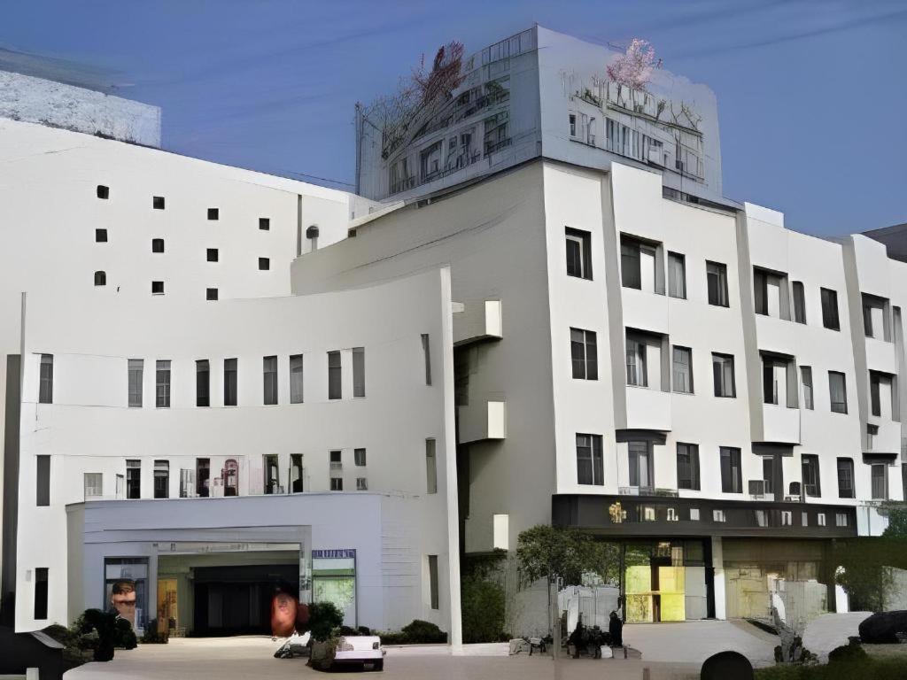 Un edificio blanco con un cartel encima. en Jinjiang Inn Central Changshu Yushan, en Changshu