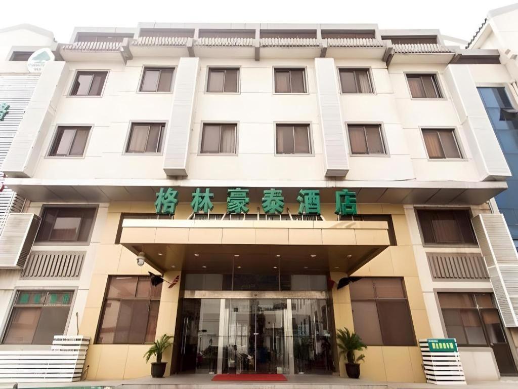 a white building with green chairs on top of it at GreenTree Inn Suzhou Guanqian Yangyuxiang Metro Station Business Hotel in Suzhou