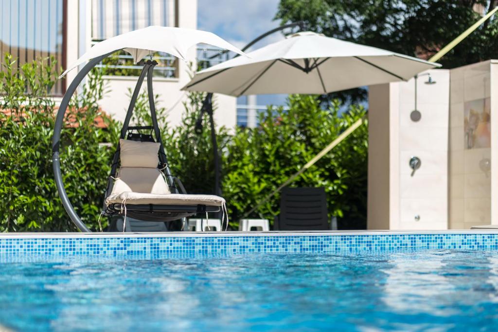 uma cadeira e um guarda-sol junto a uma piscina em Apartments Rivijera em Herceg Novi