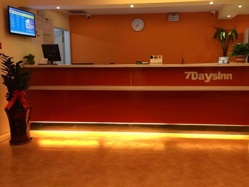 a lobby with a reception desk with a clock on the wall at 7 Days Inn Urumqi Guangming Road Beimen Metro Station in Ürümqi
