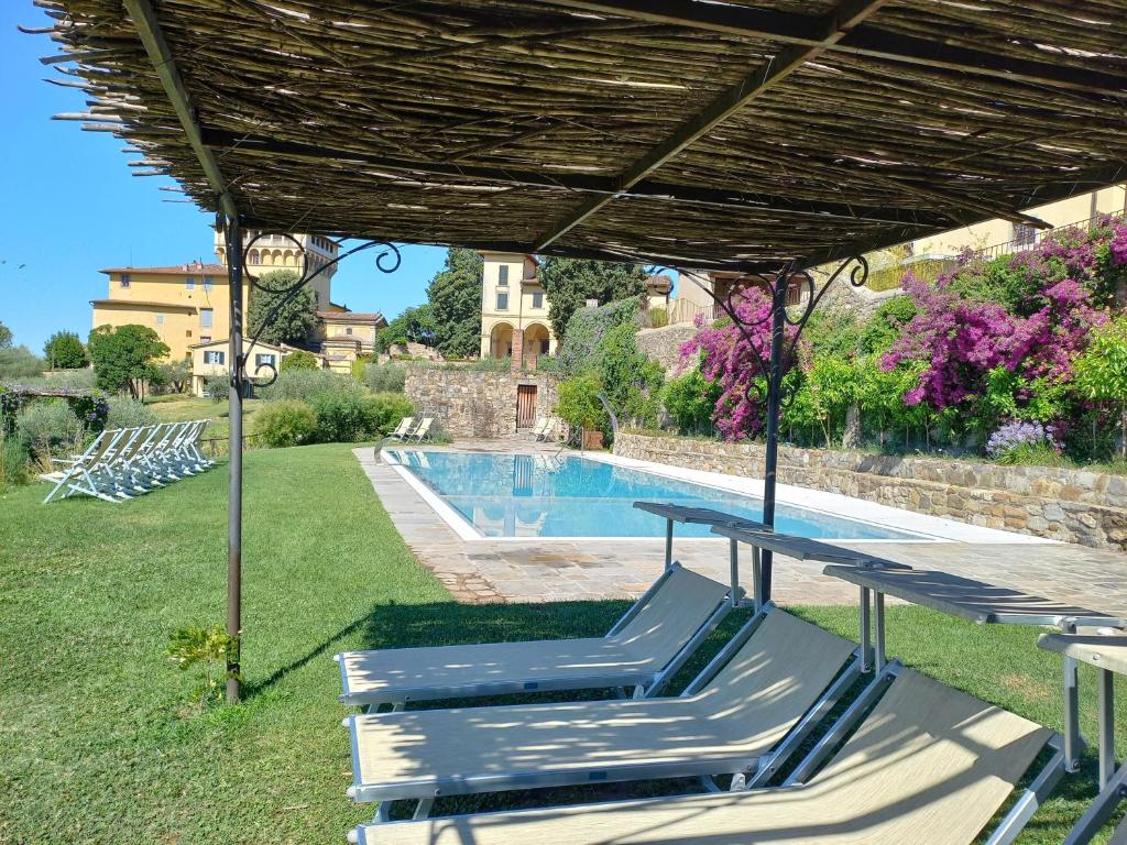 a group of lounge chairs under a pavilion next to a swimming pool at Agriturismo Fattoria Di Maiano in Fiesole