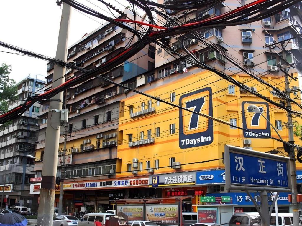 7 Days Inn Wuhan Hanzheng Street Shengli Road Metro Station في ووهان: مبنى أصفر عليه لافتات