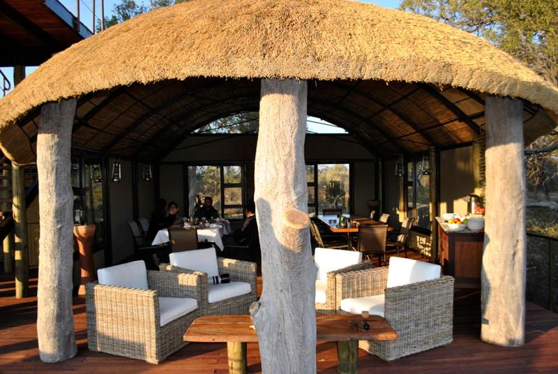 un pavillon avec des chaises, une table et un toit de paille dans l'établissement Nkasa Lupala Tented Lodge, à Sangwali