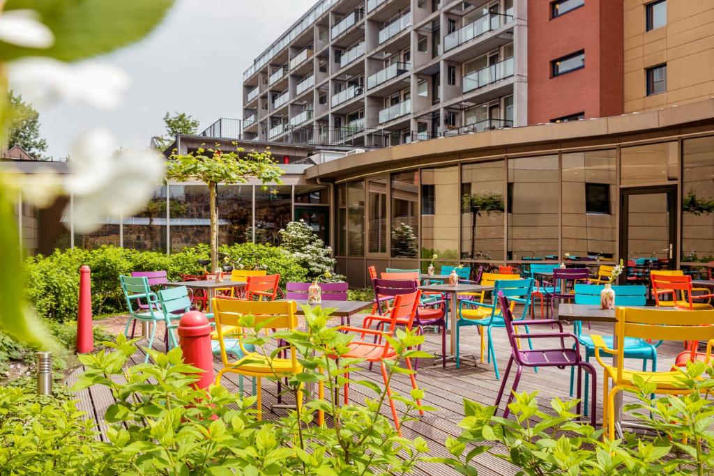 a patio with colorful chairs and tables in front of a building at ibis Amsterdam Centre Stopera in Amsterdam