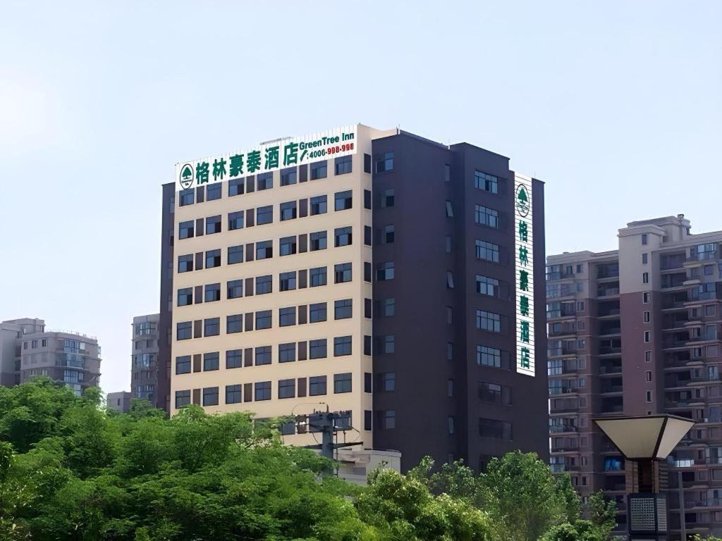 ein hohes Gebäude mit grüner Schrift an der Seite in der Unterkunft GreenTree Inn Suzhou North Zhongshan Road Weiye Yingchun Plaza Business Hotel in Suzhou
