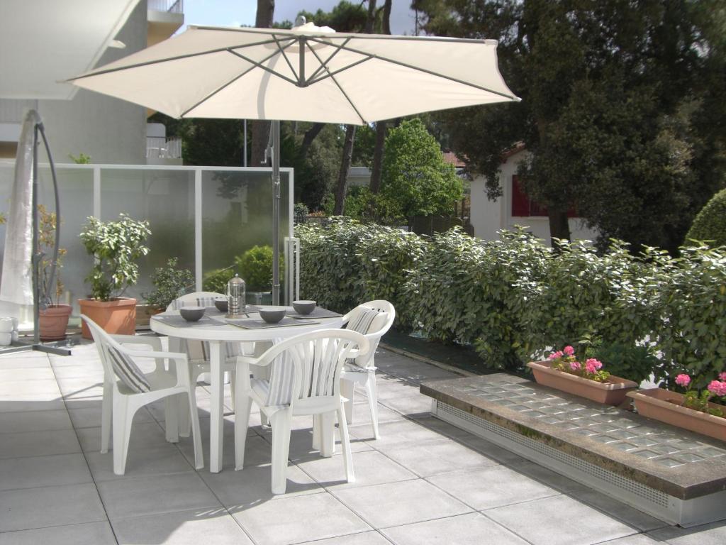 une table et des chaises blanches avec un parasol dans l'établissement Les Camellias, à La Baule
