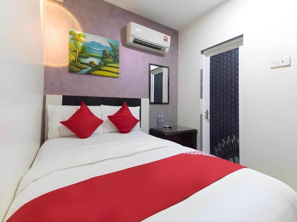 a bedroom with a large bed with red pillows at Hotel Sunsurya in Kampong Batu Belah