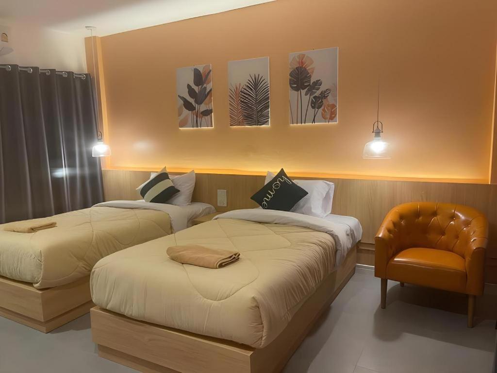 ein Hotelzimmer mit zwei Betten und einem Stuhl in der Unterkunft Kiatwimon Hotel in Sathani Phitsanulok