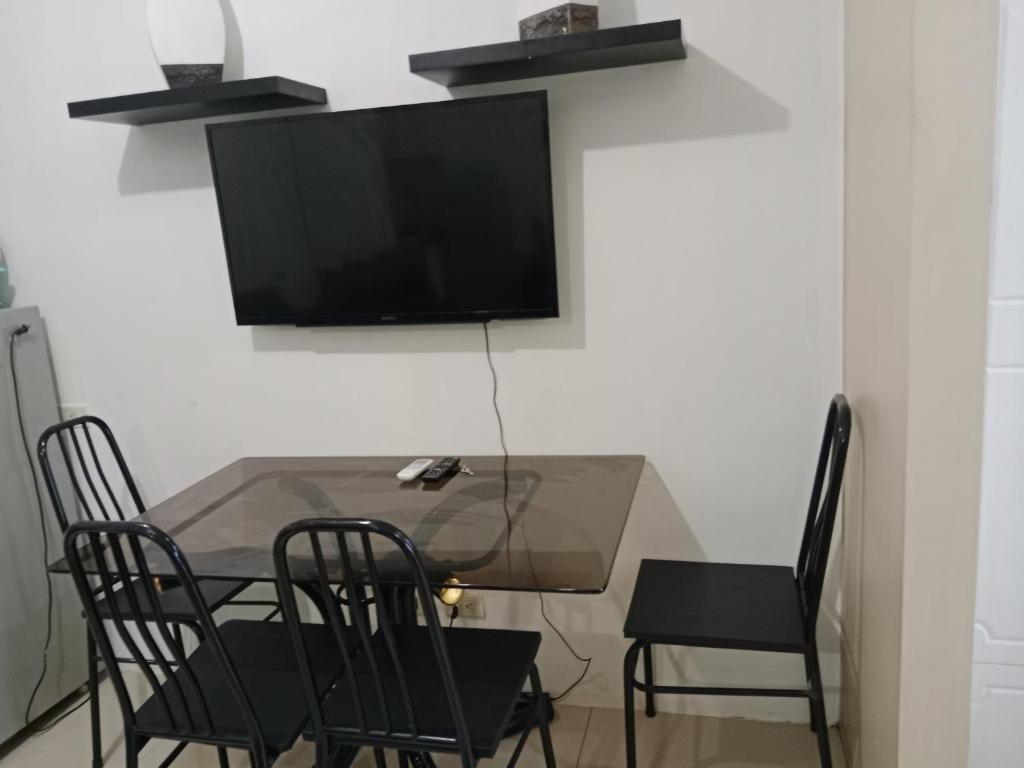 a dining room table with chairs and a television on a wall at Alyssa Sea Residence MOA condotel in Manila
