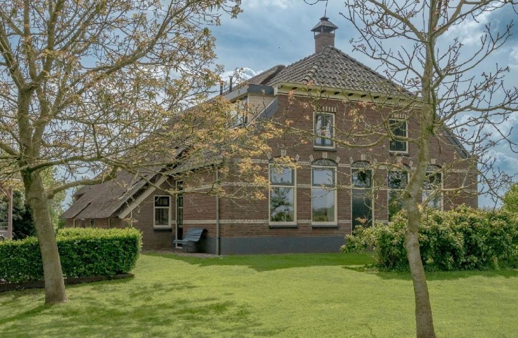 a large brick house with a tree in front of it at Achterhuis Echt mooi in Nijeveen