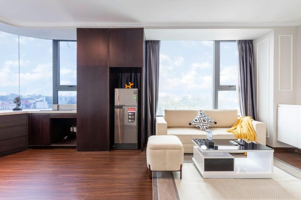 een woonkamer met een bank en een keuken met ramen bij Ivy Luxury Hotel Ha Noi in Hanoi