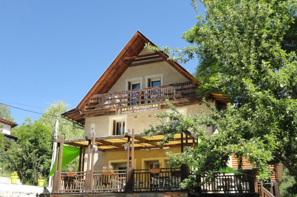 a large house with a balcony and trees at Hôtel Restaurant Le Martagon in Villars-Colmars