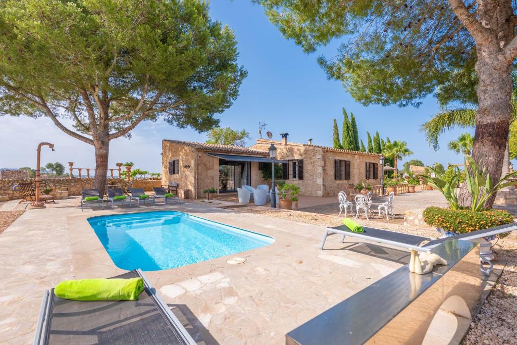 an outdoor swimming pool with chairs and a house at Banc Doli in Manacor
