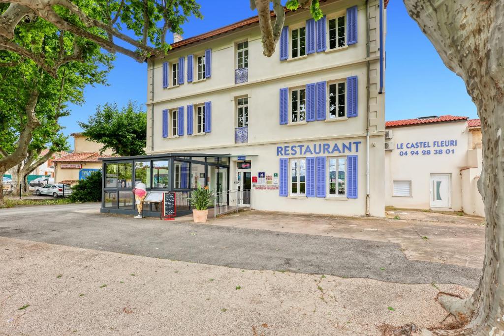 a building with blue shutters on it at Hotel Restaurant Le Castel Fleuri in Carnoules