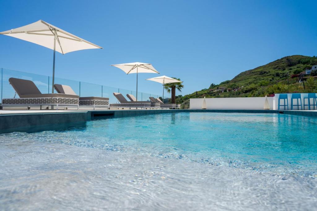 a swimming pool with chairs and umbrellas at Dolceterra Eolian Villas in Lipari