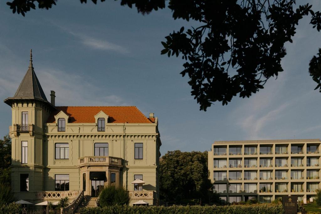 an old building with a turret next to a building at Vila Foz Hotel & SPA - member of Design Hotels in Porto