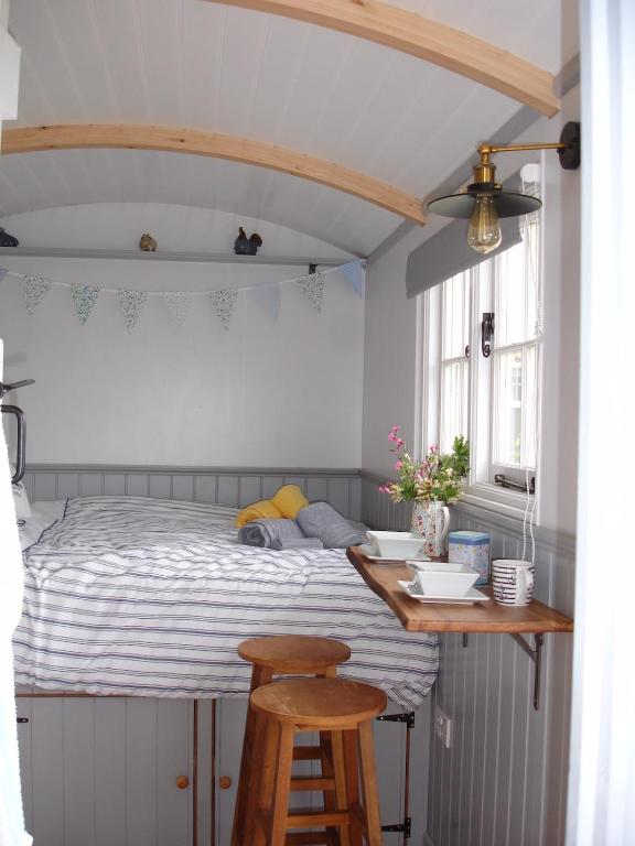 a bedroom with a bed with a table and two stools at Apple Tree Shepherd's Huts - Blackberry Hut in Saint Endellion