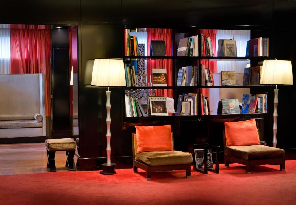 um quarto com duas cadeiras e uma estante de livros com livros em Starhotels Anderson em Milão