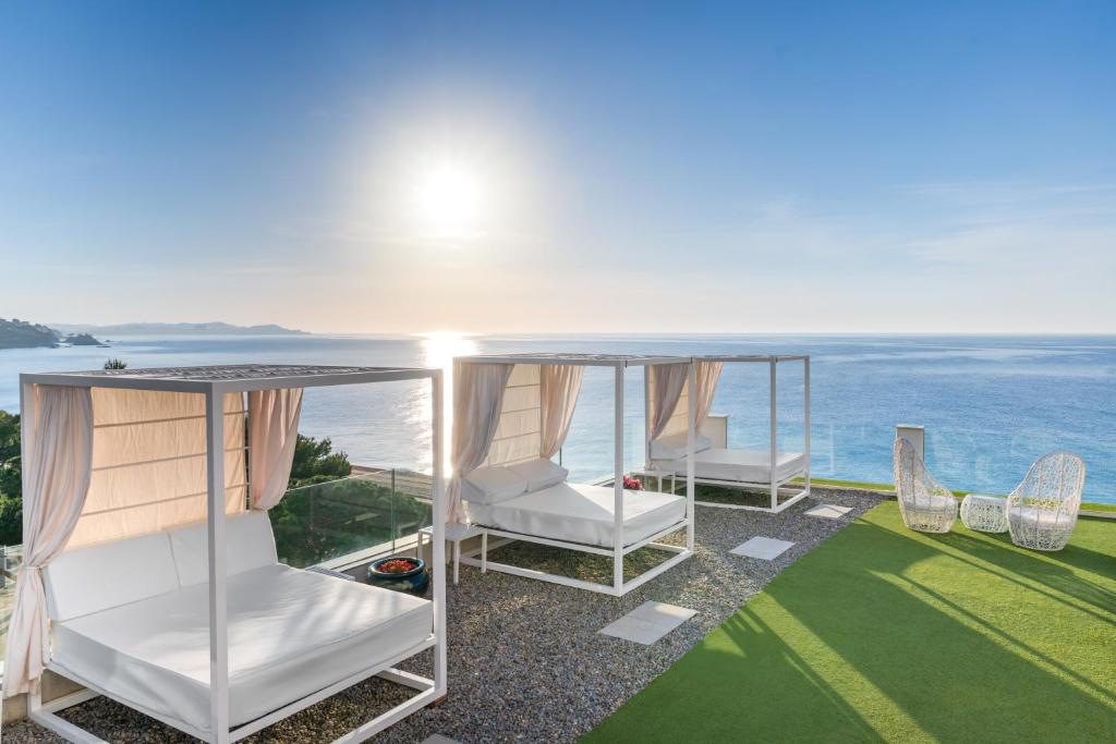 Dos sillas blancas en un patio con vista al océano. en Hotel Planamar by Escampa Hotels, en Platja d&#39;Aro