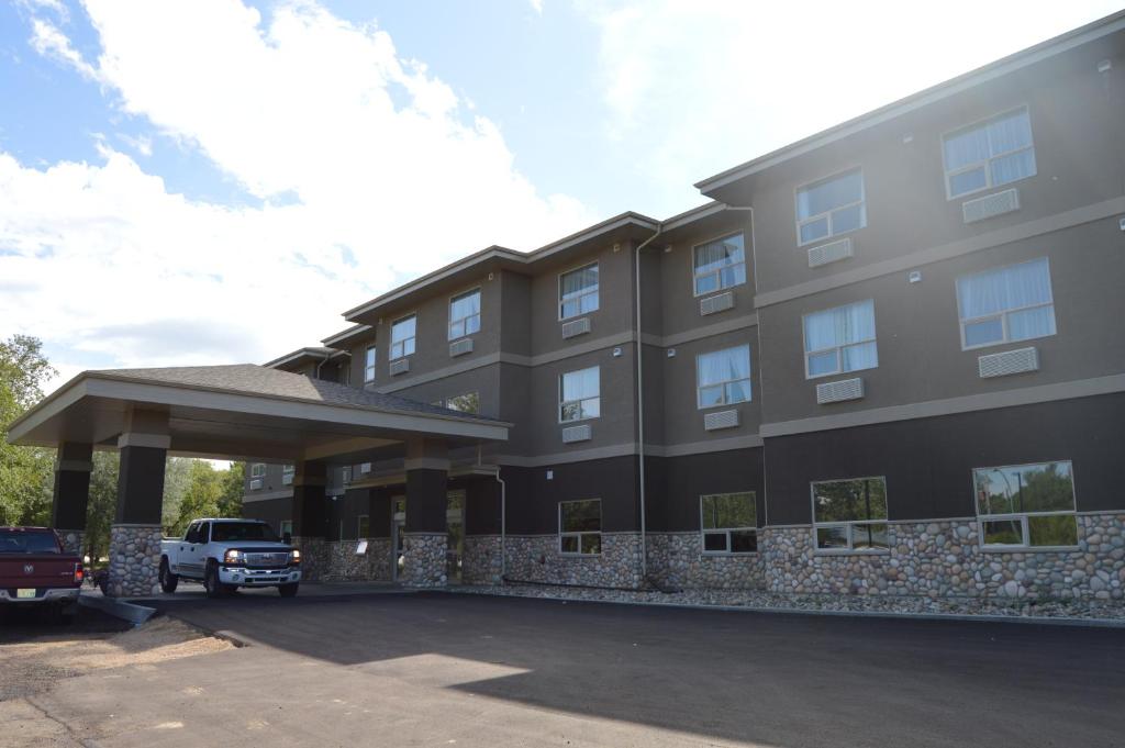 un edificio con un estacionamiento delante de él en Cobble Creek Lodge, en Maple Creek