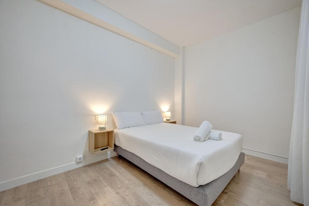 a white bedroom with a bed and a night stand at Maturana by Clabao in Logroño