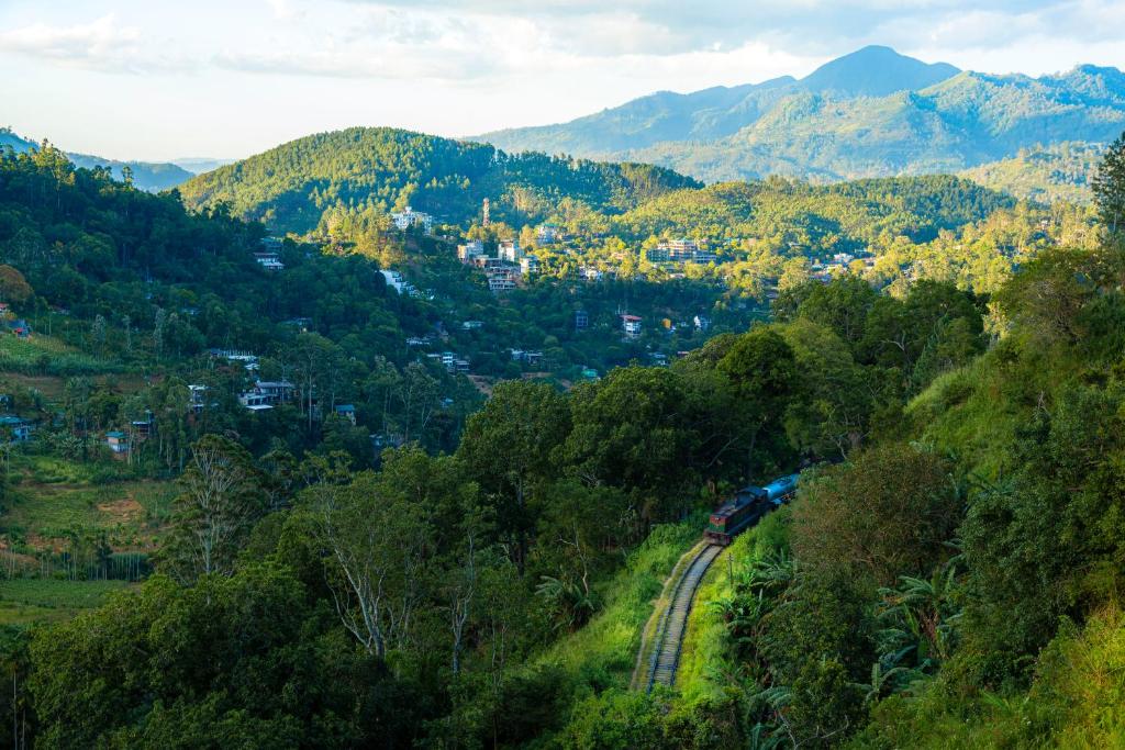a train is traveling down the tracks in the mountains at Lina Eco Cottage - Ella in Ella
