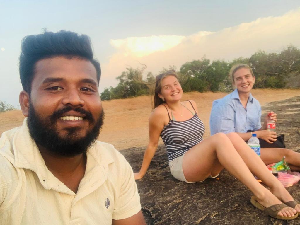 a man and two women sitting on the beach at Sigiri Village Vibe Hostel in Sigiriya