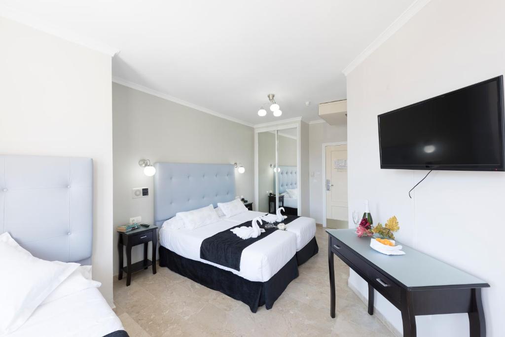 a hotel room with a bed and a flat screen tv at Hotel Toboso Chaparil in Nerja