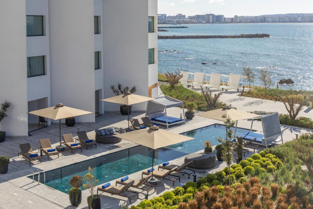 タンジェにあるIdou Malabata Beach and SPAのプール、椅子、傘を備えたホテルのイメージ