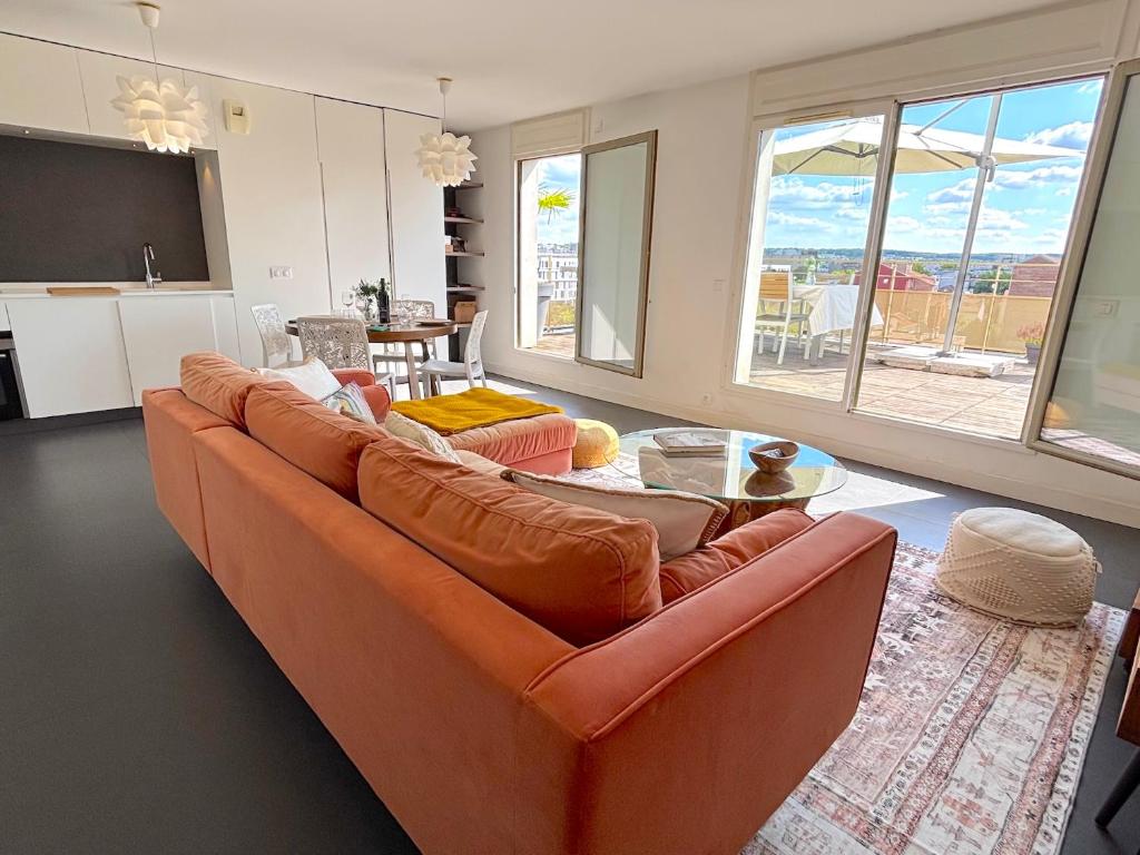 een woonkamer met een oranje bank en een tafel bij Le Penthouse Ampère in Nanterre