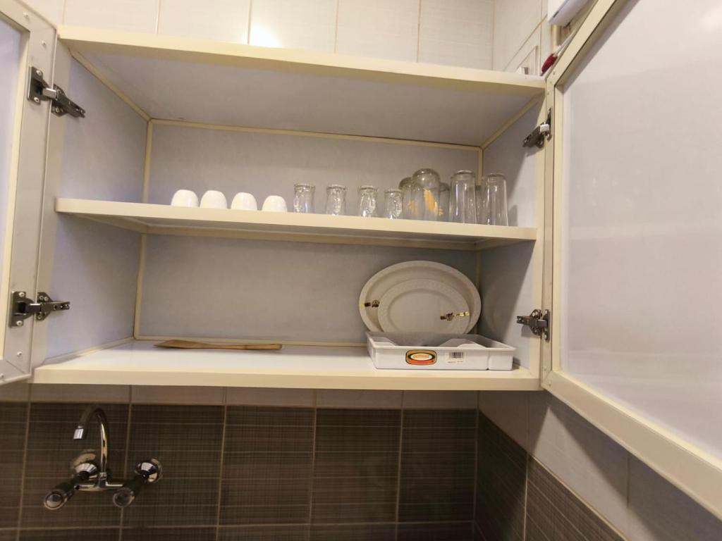 a bathroom with shelves with glasses and a sink at Qasr Aljoud Serviced Apartments in Abha