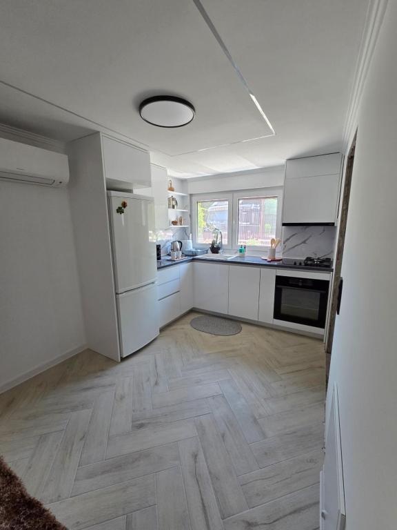 a kitchen with white appliances and a wooden floor at Green Home Bihać in Bihać