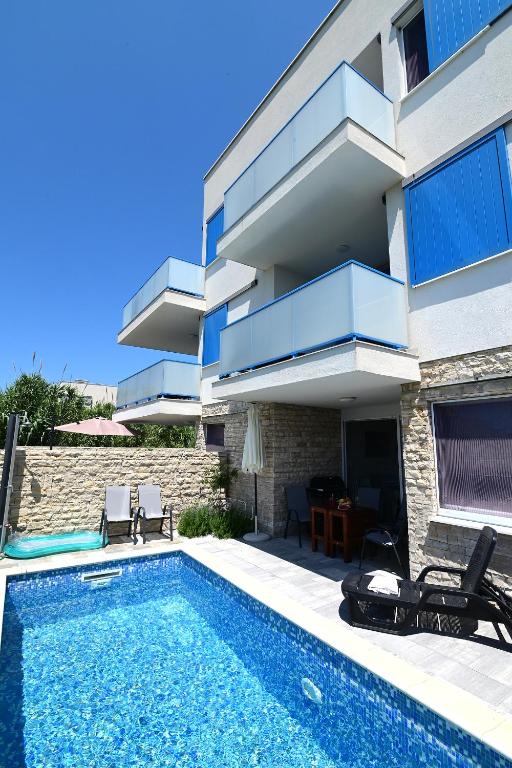 a villa with a swimming pool in front of a building at Villa Aster in Privlaka