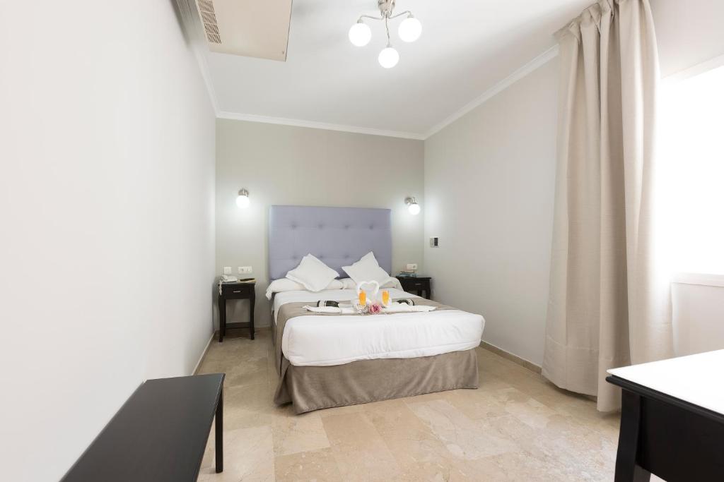 a white bedroom with two beds and a window at Hotel Toboso Chaparil in Nerja