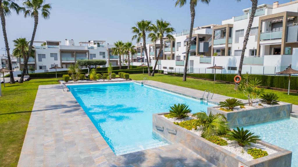 a swimming pool with palm trees in front of a building at Mirador del Mar in Torrevieja
