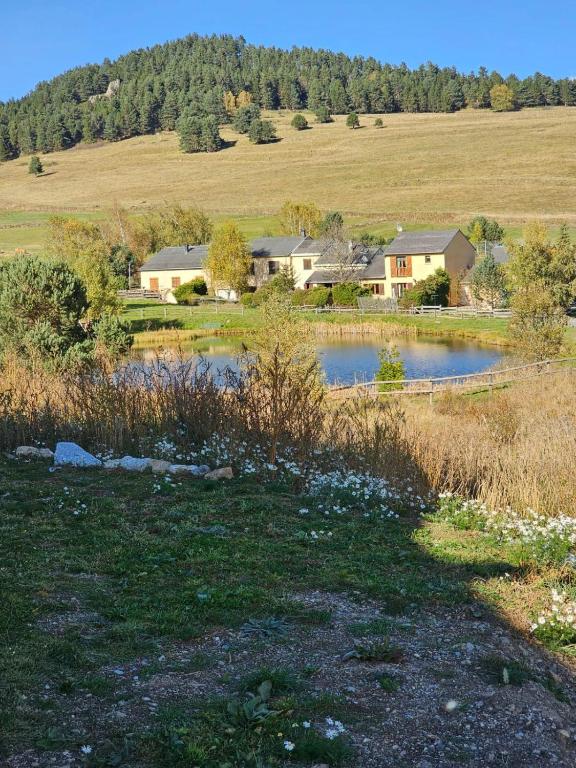 a house in the middle of a field with a pond at appartement le blanco neige in Puyvalador