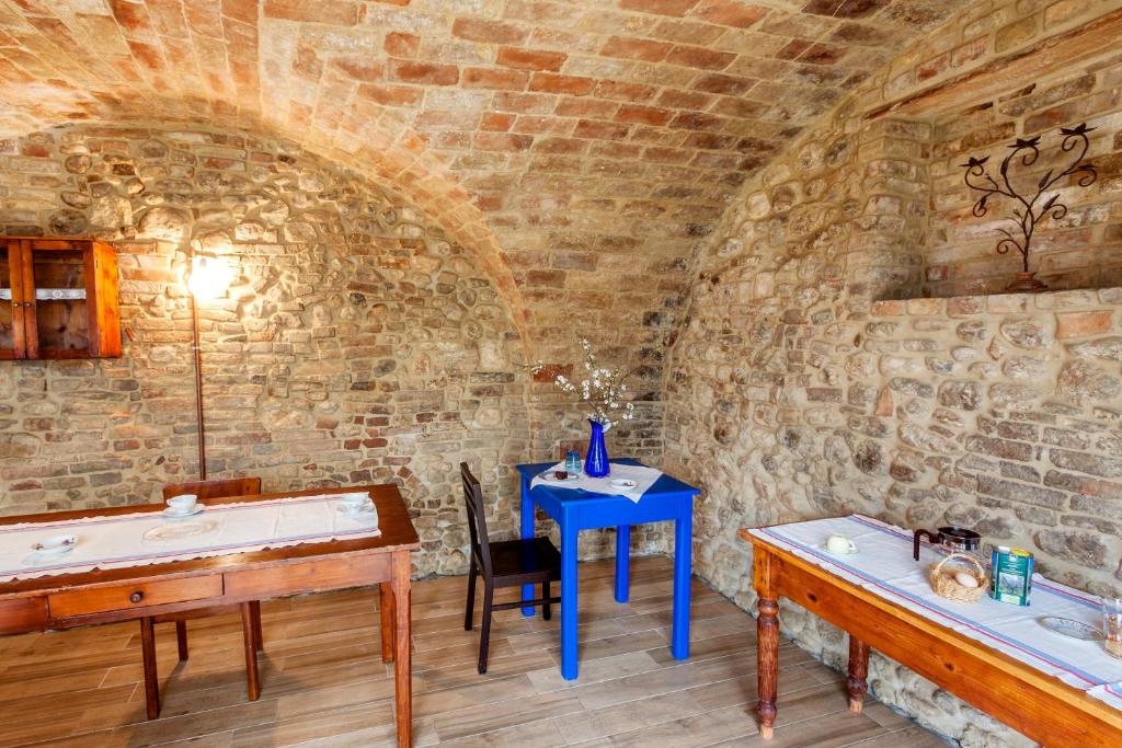Habitación con una mesa azul en una pared de piedra. en Agriturismo Bio-Melampo en Ancarano
