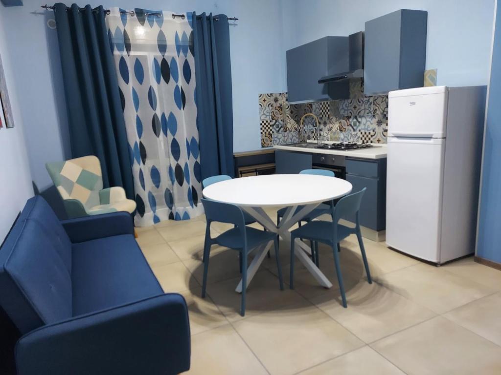 a small kitchen with a white table and blue chairs at La Casa di GiòEle in Giardini Naxos