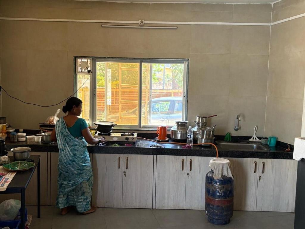 a woman standing in a kitchen preparing food at Pali Retreat Riverside Stay with Pool in Pali