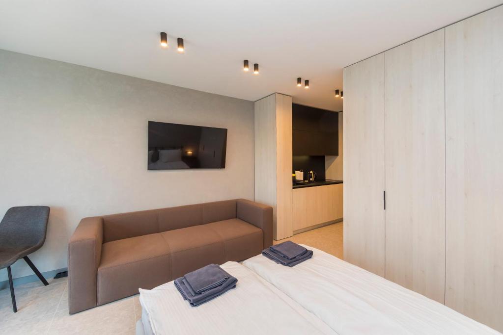 ein Schlafzimmer mit einem Bett, einer Couch und einem Fernseher in der Unterkunft Eleve Residences - Obsidian Studios in Sofia