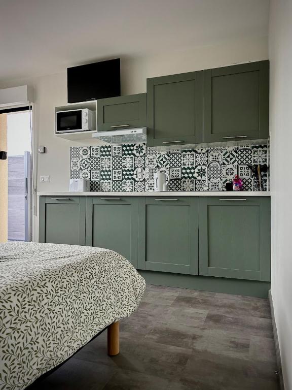 a kitchen with green cabinets and a bed in a room at L'Escale de la Râperie, logement 3 in Tincourt-Boucly