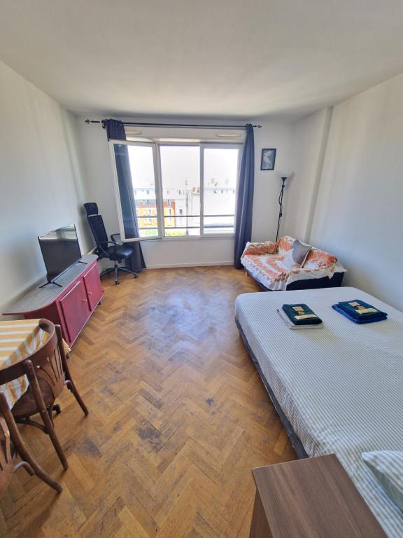 Cette chambre comprend deux lits, un bureau et une table. dans l'établissement Magnifique studio aux portes de Paris, à Aubervilliers