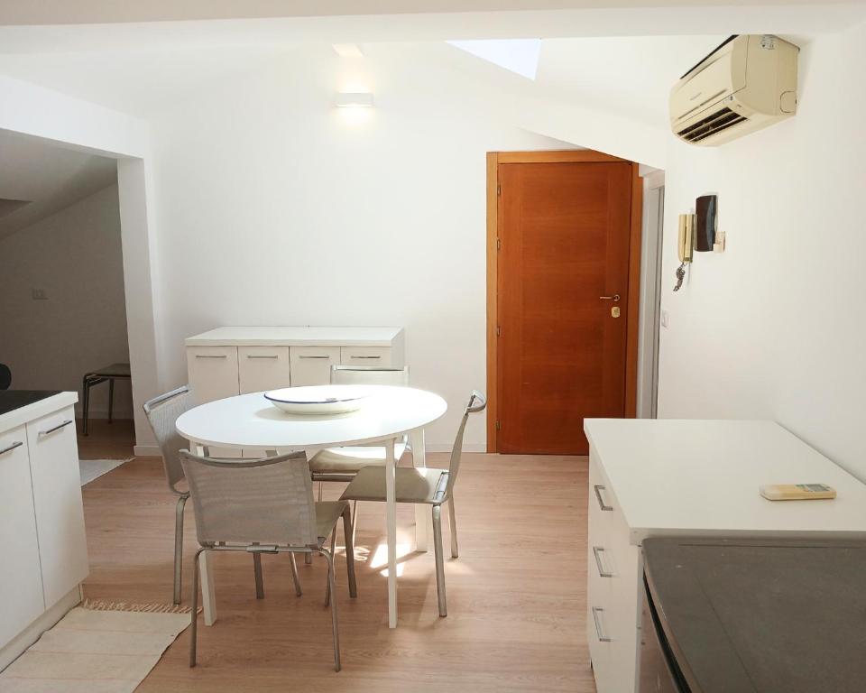 a white kitchen with a white table and chairs at CV017 - Milano Marittima, elegante mansarda con aria condizionata in Cervia
